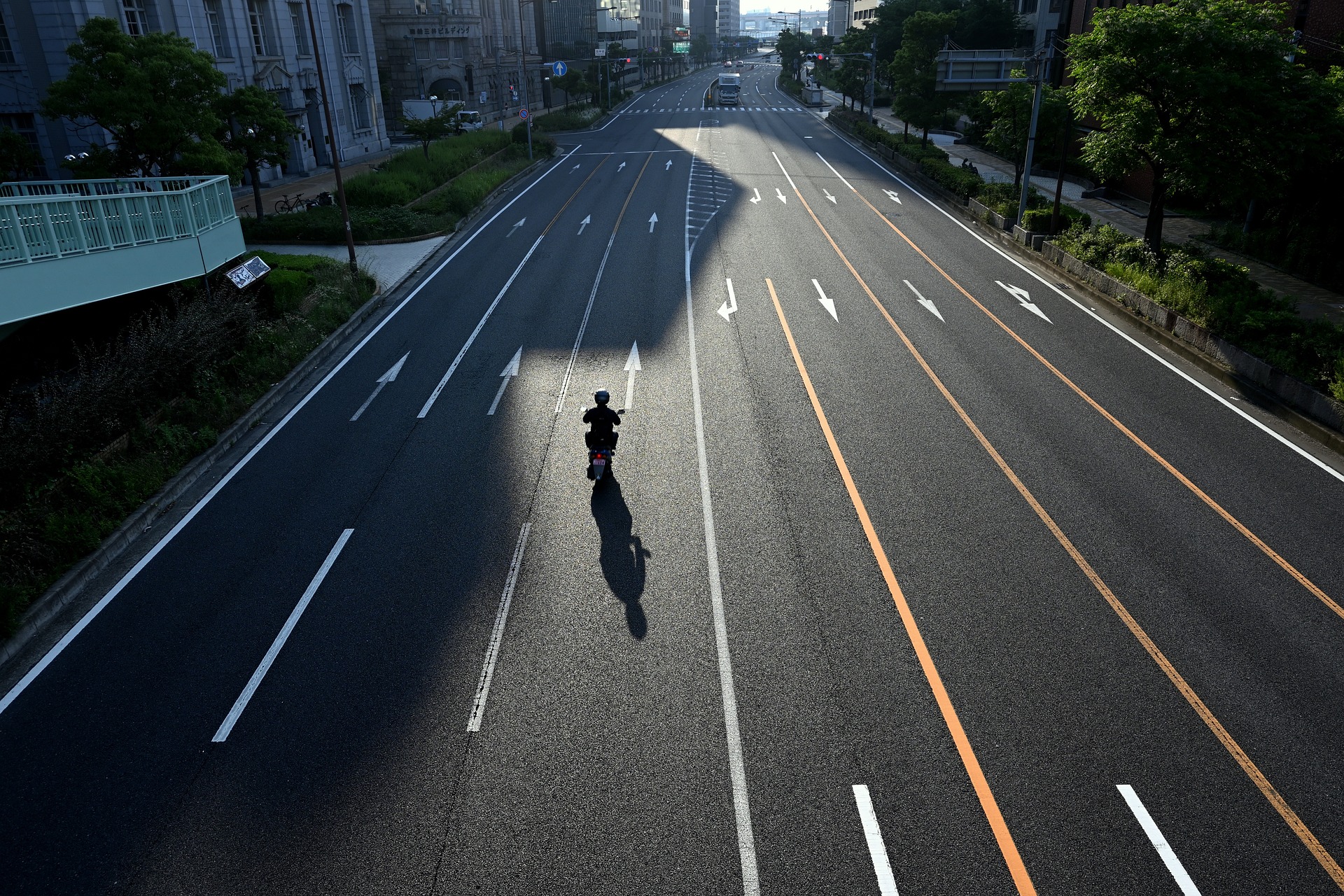 image d'une petite moto au milieu d'une large route à six voies
